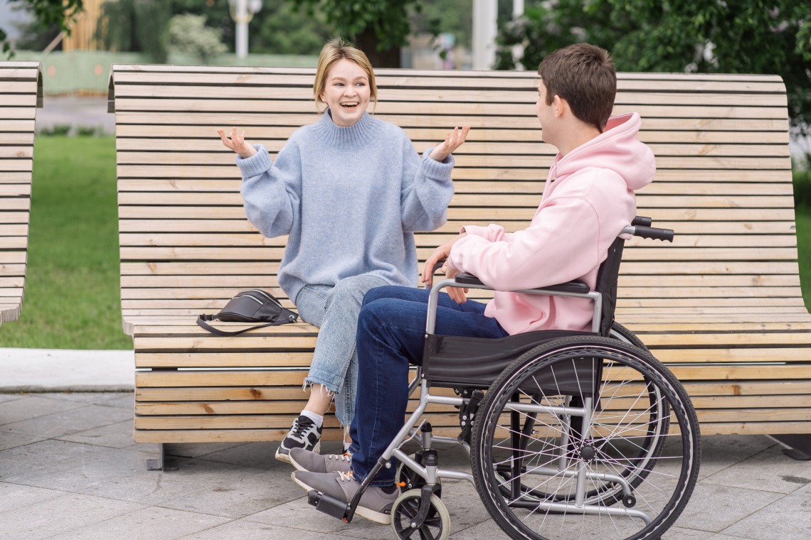 a person sitting on a bench talking to a person using a wheelchair
