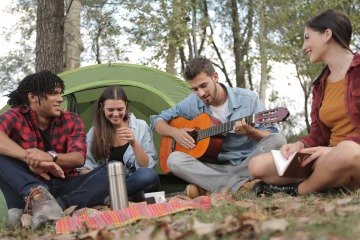 group of people playing the guitar by a tent