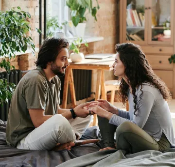 Women and man having a conversation sitting in bed 